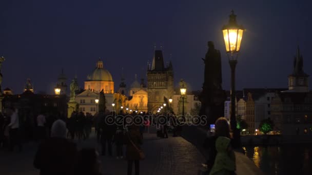 Avond stadsgezicht met mensen lopen op de schilderachtige Karelsbrug, Prague, Tsjechië — Stockvideo