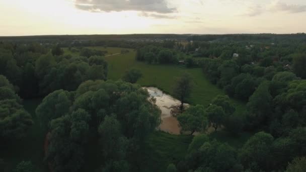 Vue sur la forêt, le lac et les maisons de campagne contre le ciel bleu avec soleil et nuages au coucher du soleil en été, Russie 
