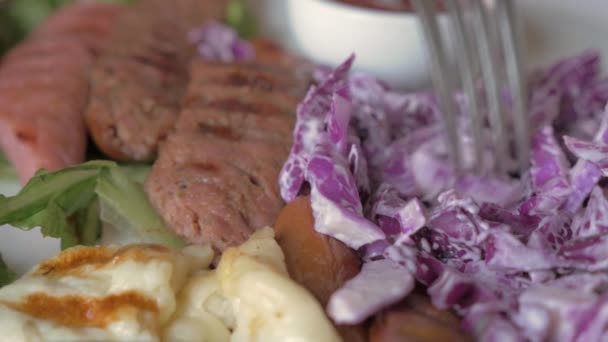 Comer salchichas y ensalada de col roja — Vídeos de Stock