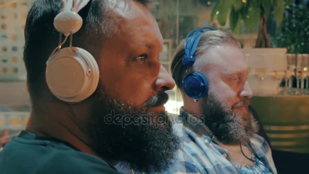 Hombres barbudos en auriculares disfrutando de la música — Vídeo de stock