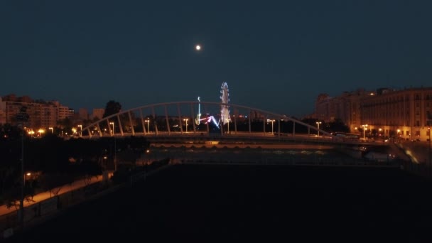 Luftaufnahme von beleuchteten Riesenrad und Brücke gegen den Himmel mit Mond, Valencia, Spanien — Stockvideo