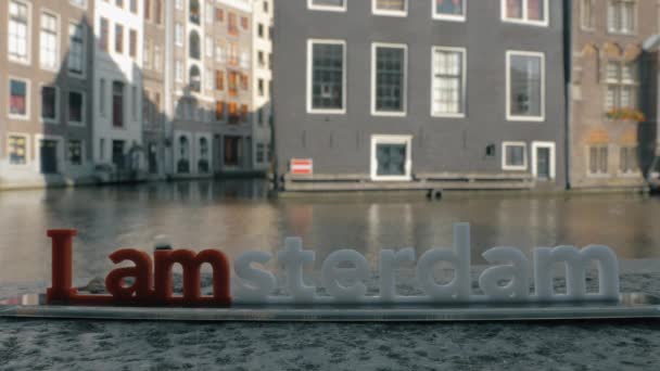 Вид на невелику пластикову фігуру з листів Ямстердама скульптура на мосту проти розмитого цитаделі, Амстердам, Нідерланди. — стокове відео