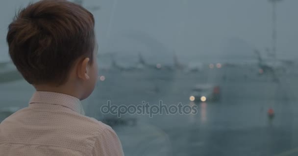 Criança é atraída com vista para o aeroporto na janela — Vídeo de Stock