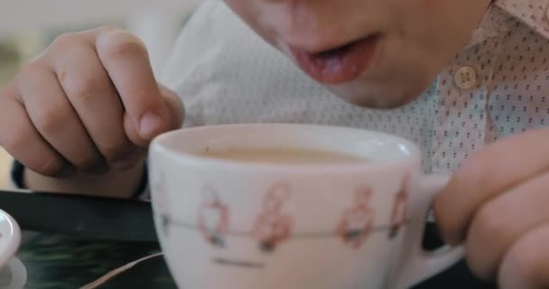 Menino soprando no chá quente e resfriando-o — Vídeo de Stock