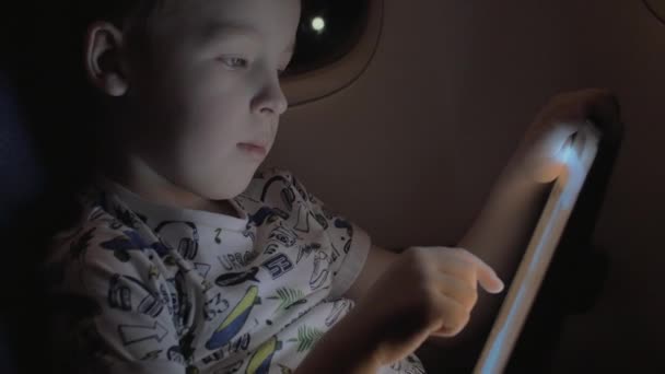 Αγόρι ταξιδεύουν με αεροπλάνο και να παίζει το παιχνίδι στο tablet Pc — Αρχείο Βίντεο