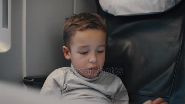 Menino usando tablet PC tentando entreter-se durante a viagem de trem chato — Vídeo de Stock