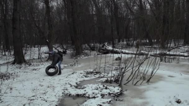 Garçon adolescent emportant pneu usagé de la manière dans le parc d'hiver — Video