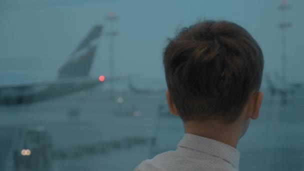 Al chico le gusta mirar aviones cuando espera el vuelo. — Vídeos de Stock