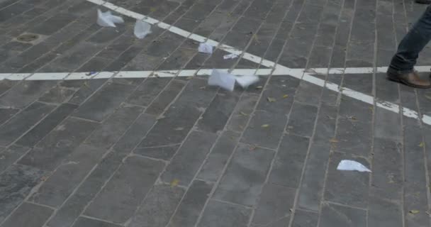 Voeten van mensen lopen in de straat met papier strooisel — Stockvideo
