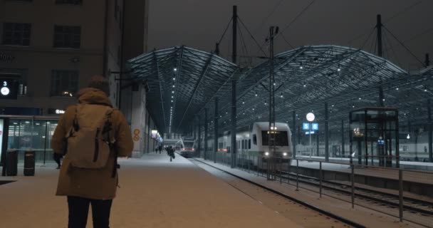 Tren saliendo de la estación por la noche y el hombre haciendo vídeo en el móvil — Vídeos de Stock