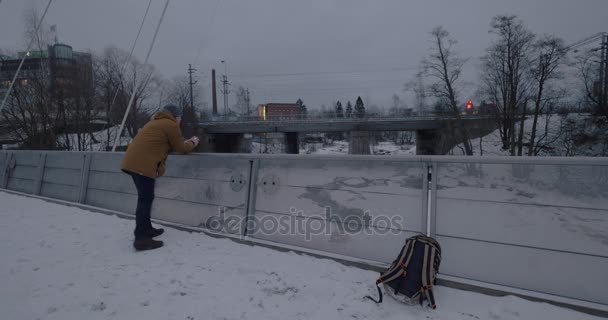 Man with cell taking video of moving train in winter city — Stock Video