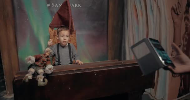 Mamá tomando una foto de niño con sombrero de elfo en Santa Park, Rovaniemi — Vídeos de Stock