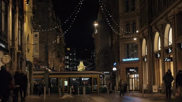 Rua com pessoas ambulantes e eléctrico de passagem à noite. Helsínquia, Finlândia — Vídeo de Stock