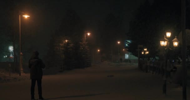男の夜の冬の公園で携帯電話での撮影 — ストック動画