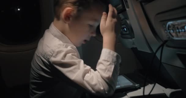 Menino viajando de avião e jogando jogo de xadrez em tablet digital — Vídeo de Stock