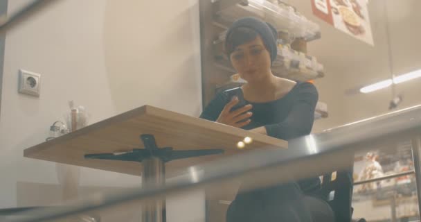 Femme gaie dans le café communiquant en ligne sur téléphone portable — Video