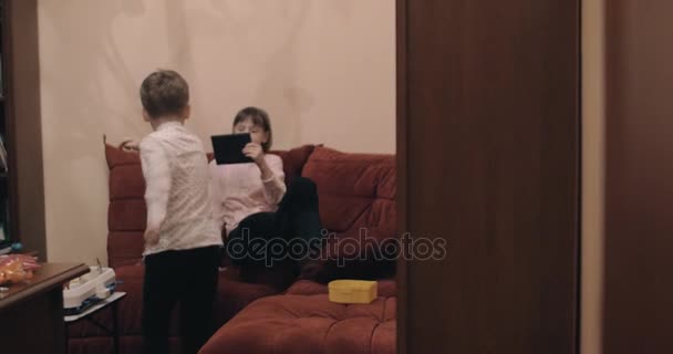 Мальчик дурачится и танцует, когда девушка снимает видео с планшетного компьютера — стоковое видео