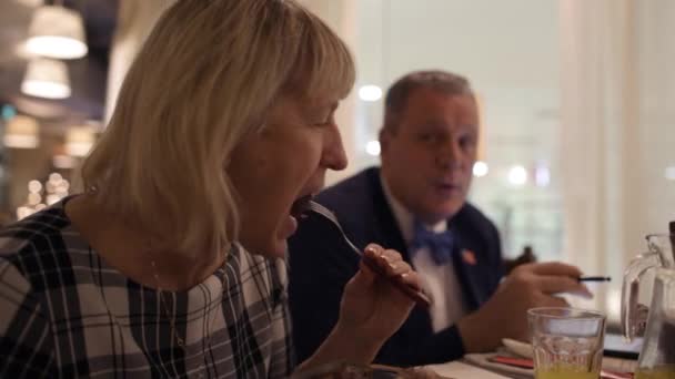 Жінка їсть і чоловік розмовляє в бізнесі за допомогою майданчика — стокове відео
