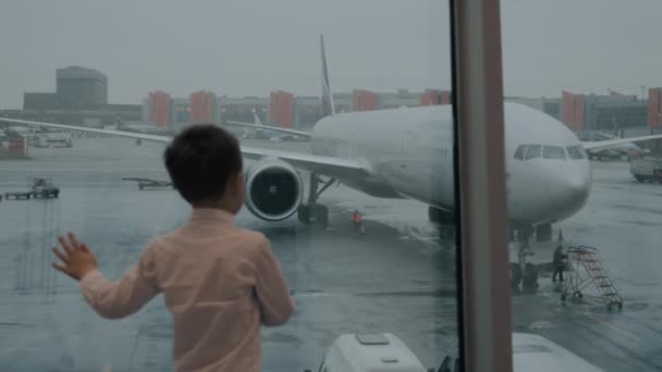 Niño mirando el avión por la ventana — Vídeos de Stock