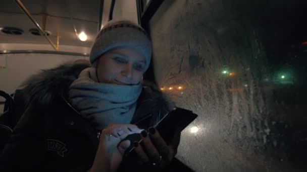 Žena s mobilní cestování autobusem v zimě večer
