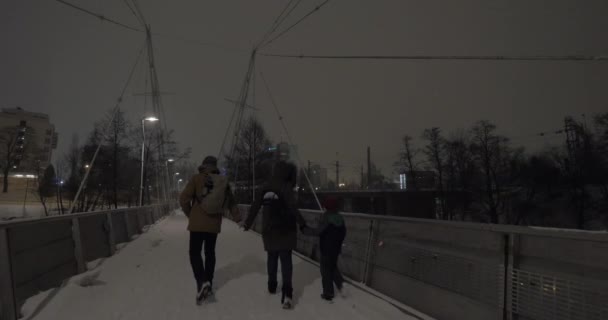 Eltern mit Kind Händchen haltend und in der winterlichen Abendstadt spazieren — Stockvideo