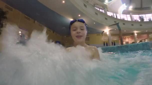 Criança alegre desfrutando de hidromassagem na piscina — Vídeo de Stock