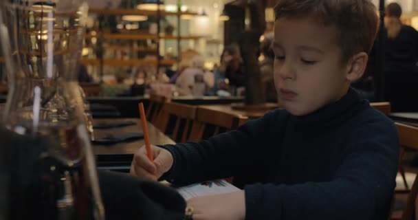 Dibujo infantil cuando está sentado en la cafetería — Vídeo de stock