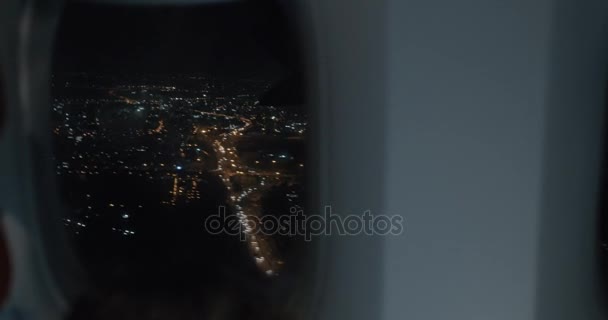 Vue de l'intérieur de l'avion. Ville de nuit en illuminateur et garçon avec tablette PC — Video