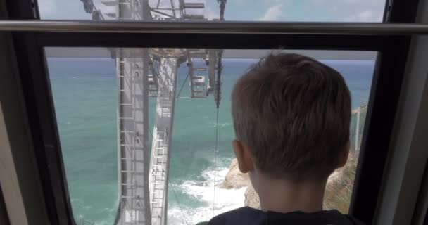 Хлопчик дивлячись на морі з рухомого фунікулер в Рош-га — стокове відео