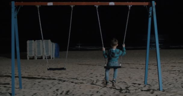 Einsames Kind, das nachts am Strand schwingt — Stockvideo