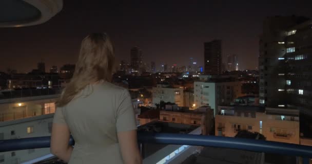 夜の街の屋上からの景色を楽しみながらの女性。テルアビブ、イスラエル — ストック動画
