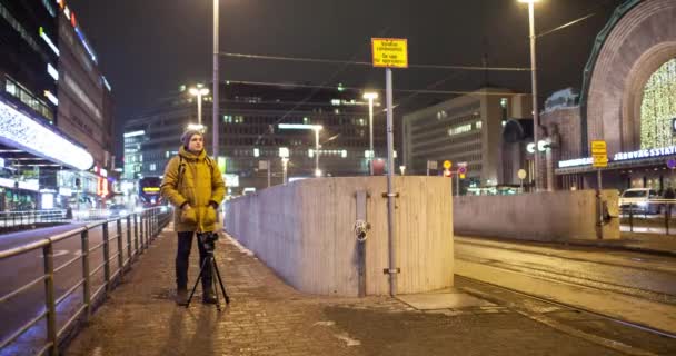 Timelapse de homem filmando vídeo à noite Helsínquia com tráfego de transporte — Vídeo de Stock