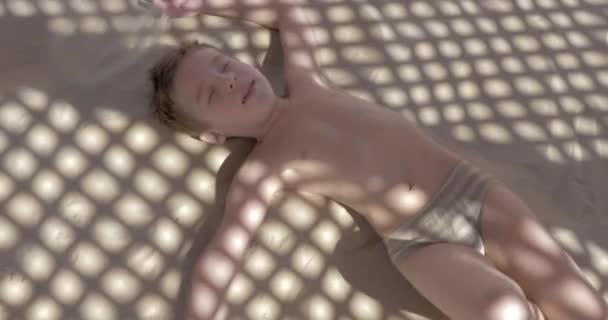 Kid crawling on warm sand under the net shed — Stock Video