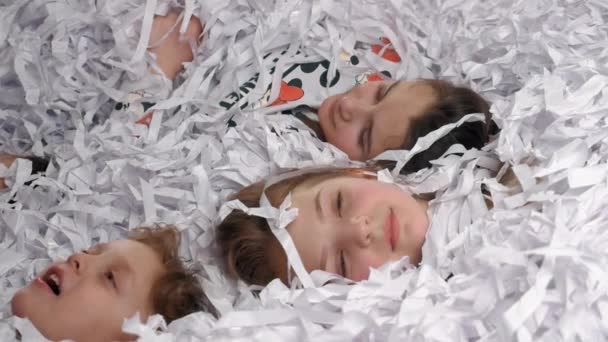 Les enfants fatigués allongés dans le papier après avoir fait une grande fête — Video