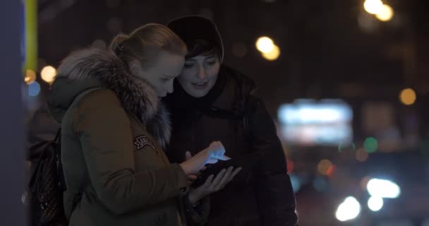 Vrouwen vrienden met behulp van tablet Pc wanneer wachten op bus in de straat — Stockvideo