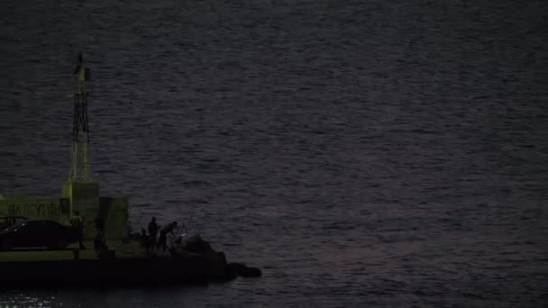 Men fishing from the quay with blinking sea-light, Greece — Stock Video