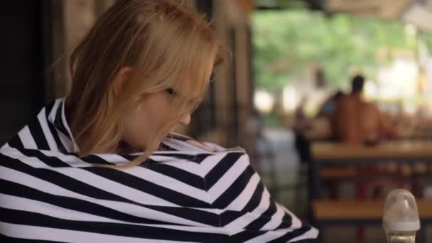 Женщина кормит ребенка в кафе с помощью молочного сноуда — стоковое видео