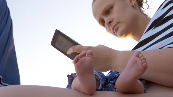 Mum with sleeping baby at the beach. Woman using cellphone — Stock Video