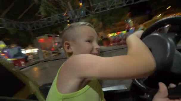 Niño divirtiéndose con coche de parachoques de conducción en feria de diversión — Vídeos de Stock