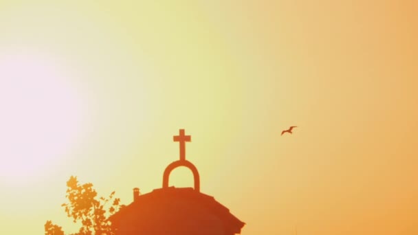 Chiesa e uccello volante contro luminoso tramonto brillare — Video Stock