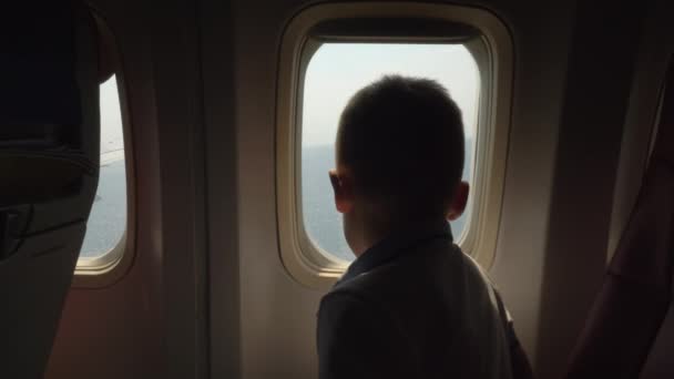 Ребенок смотрит через светильник, когда самолет собирается приземлиться — стоковое видео