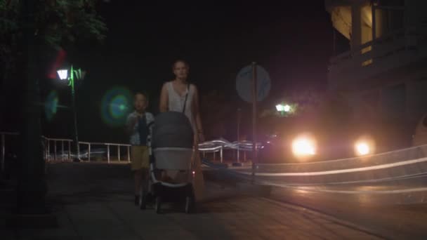 Madre con hijo mayor y bebé caminando por la noche — Vídeos de Stock
