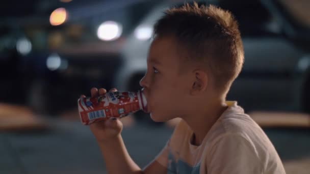 Niño bebiendo yogur al aire libre por la noche — Vídeos de Stock