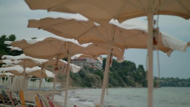 Wietrznej pogody na brzegu morza. Pustej plaży i drżenie parasole, Grecja — Wideo stockowe