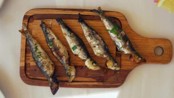 Pouring lemon juice on grilled sardines — Stock Video