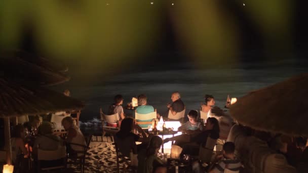 Strandkafé med människor avkopplande och having drycker vid havet på natten — Stockvideo