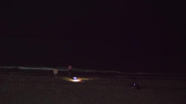 Люди на пляже ночью — стоковое видео