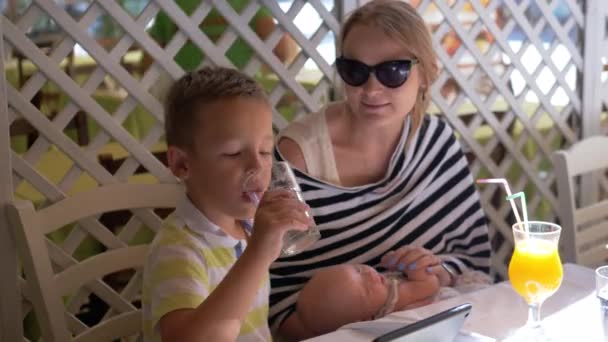 Keluarga memiliki hari yang baik. Ibu dengan bayi dan anak sulung bersantai di kafe — Stok Video