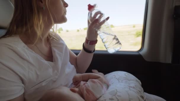 Vrouw drinkwater tijdens borstvoeding in de auto — Stockvideo