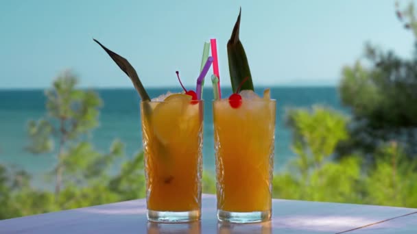 Два бокала ледяных фруктовых напитков на морском фоне. Время отпуска — стоковое видео